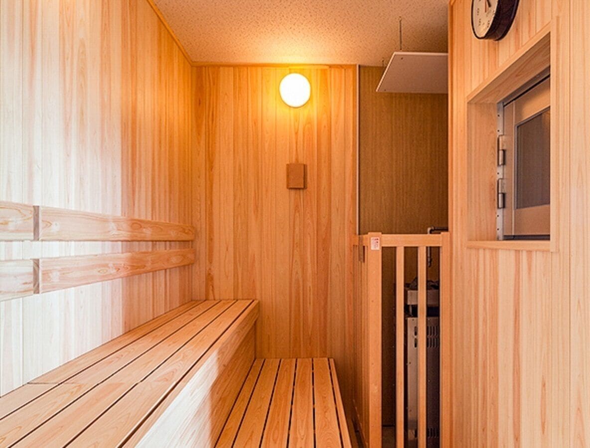 A wooden sauna with benches and a door leading to a changing room.