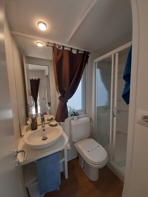 A compact bathroom with a sink, toilet, and shower.