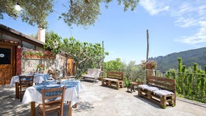 An outdoor patio with tables and benches, surrounded by stone walls and potted plants. - 4 bedroom beautiful home in Ciminà (Ciminà)