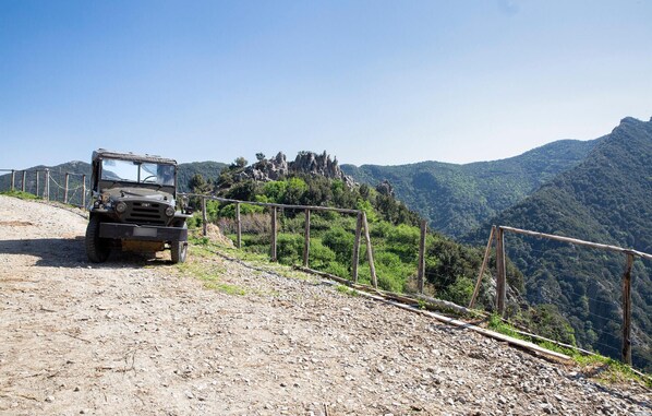 A Fiat vehicle on a dirt road with a wooden fence and a mountainous landscape in the background.