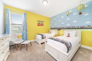 Une chambre avec deux lits, un bureau, une chaise et une fenêtre avec des rideaux.