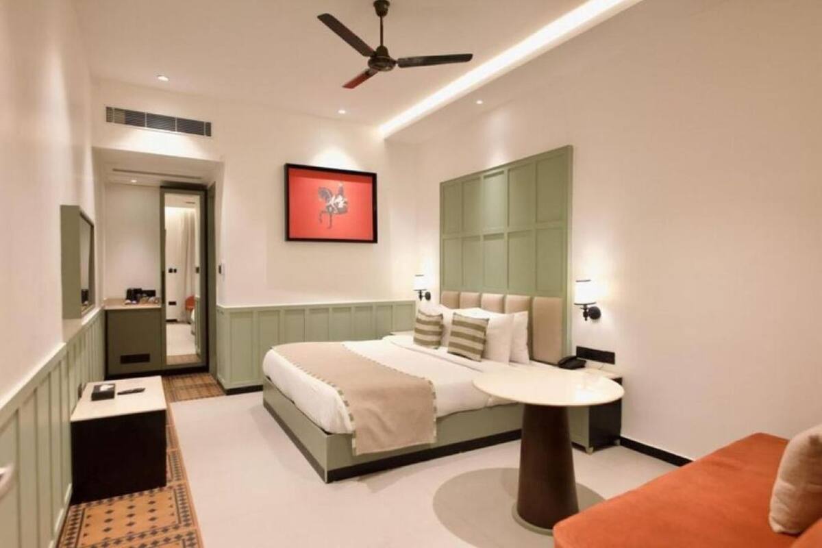 Una habitación de hotel moderna con una cama, mesita de noche y una mesa redonda.