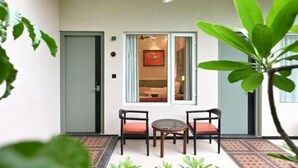 A room with a bed, a window, a door, and a small table with chairs. - Status Club Resort (Kanpur)