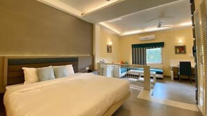 A hotel room with a large bed, a desk, a chair, and a ceiling fan. - Status Club Resort (Kanpur)