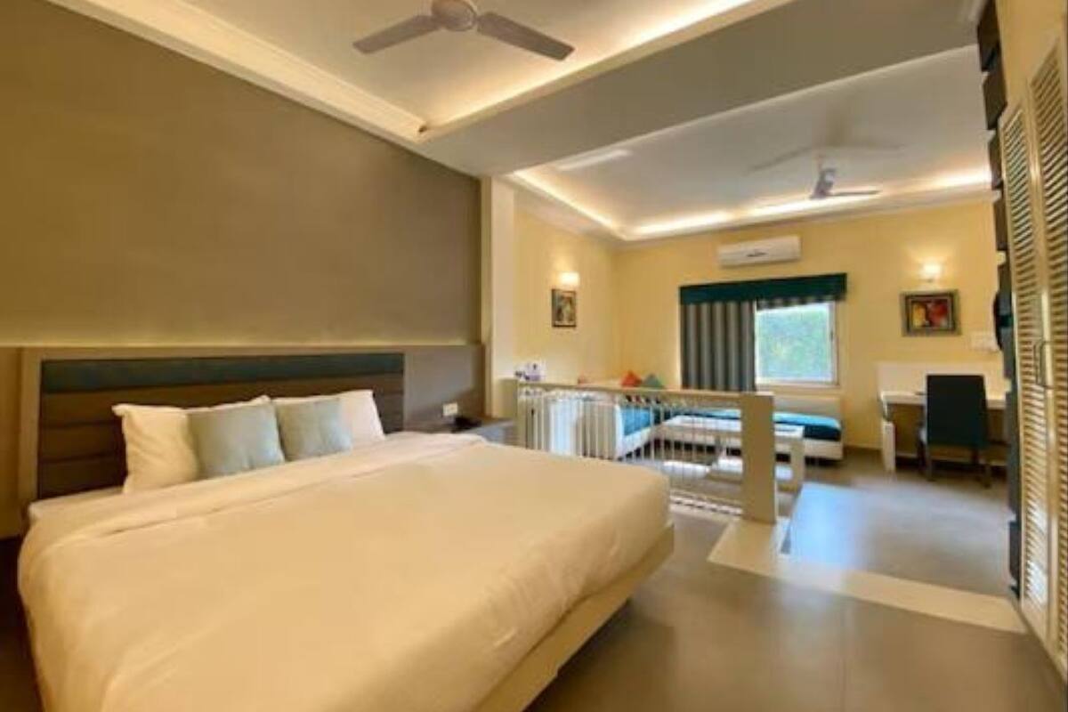 Una habitación de hotel con una cama grande, un escritorio, una silla y un ventilador de techo.