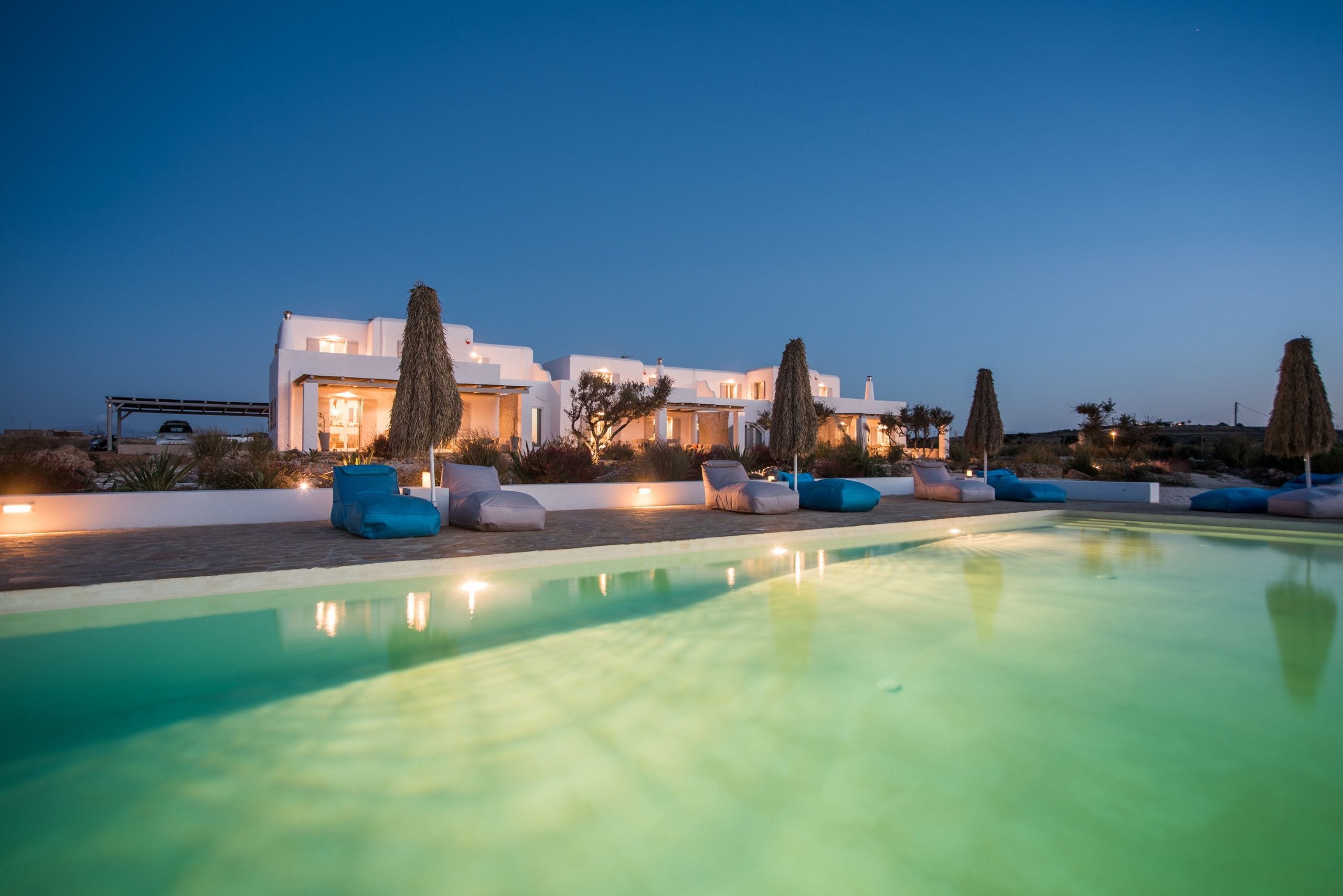Una villa moderna con piscina, mobiliario exterior e iluminación en la entrada.