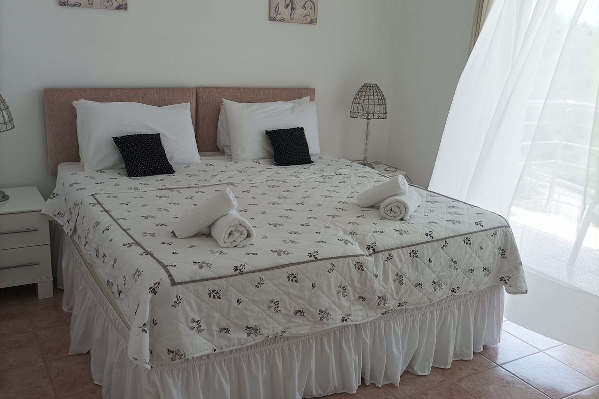 Una cama bien hecha con ropa de cama floral, un cabecero de madera y dos lámparas de pared.