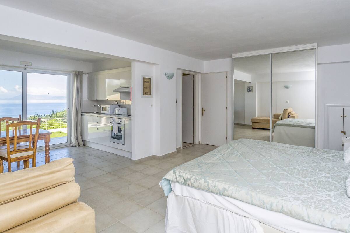 Un dormitorio con cama, un comedor con sillas, una cocina y vistas al mar.