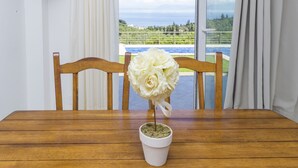 Een houten eettafel met een witte pot met witte bloemen.