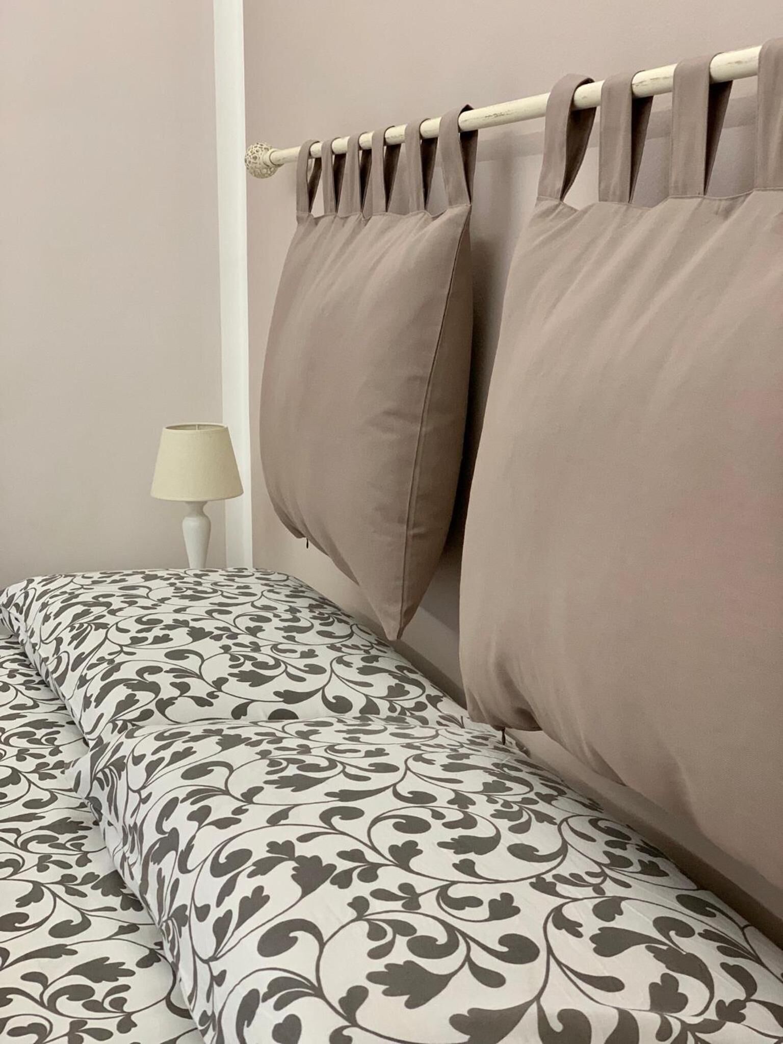 A bed with patterned bedding and a headboard with curtains.