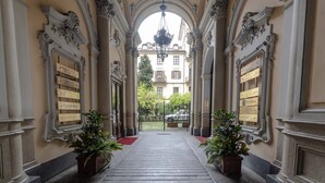 Un vaste hall d’entrée, orné de colonnes richement décorées et surmonté d’un lustre, qui mène à l’entrée du bâtiment.