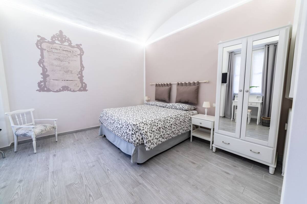 A bedroom with a bed, a chair, a wardrobe, and a wall decoration.
