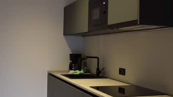 Una cucina moderna con forno a microonde, macchina del caffè e lavello.