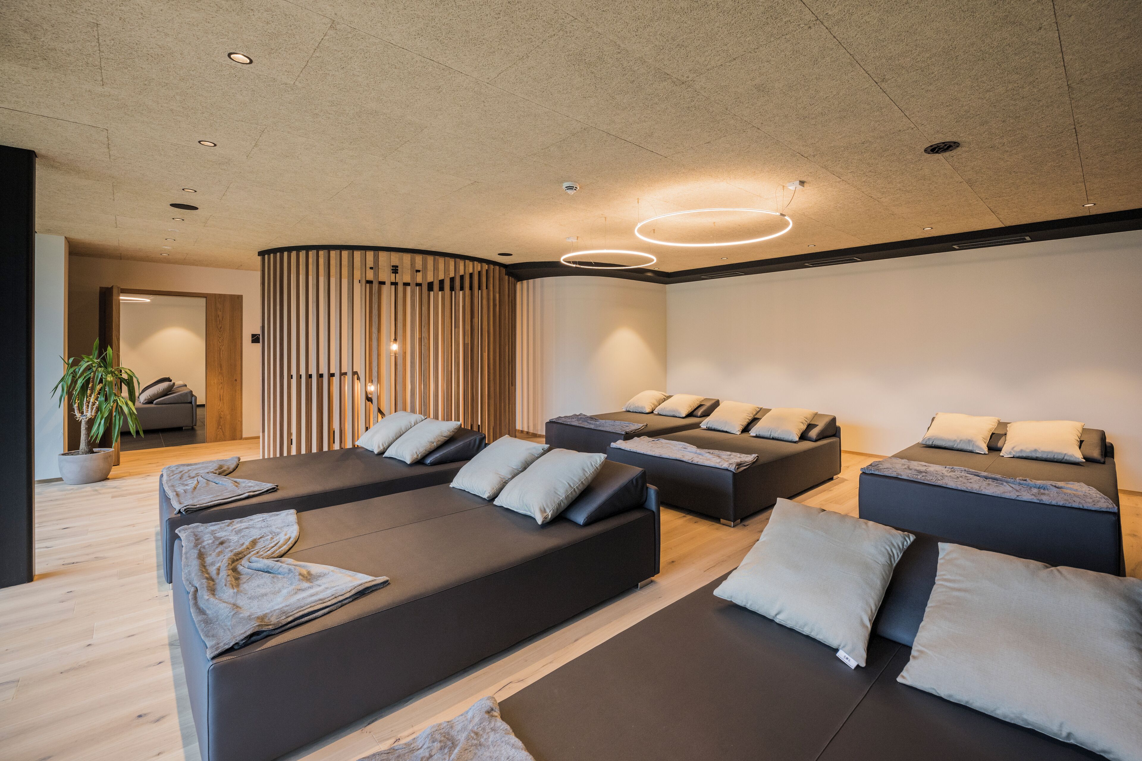 Un moderno spa con varios sofás negros y una pared de listones de madera.