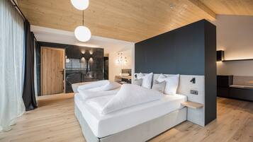 A modern bedroom with a large bed, wooden flooring, and a stone fireplace.