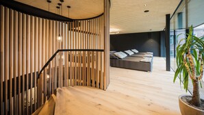 Um interior moderno com escada de madeira, área de sofás e planta em vaso.
