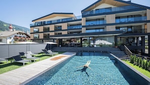 Um hotel moderno com piscina, área de estar externa e vista para as montanhas.