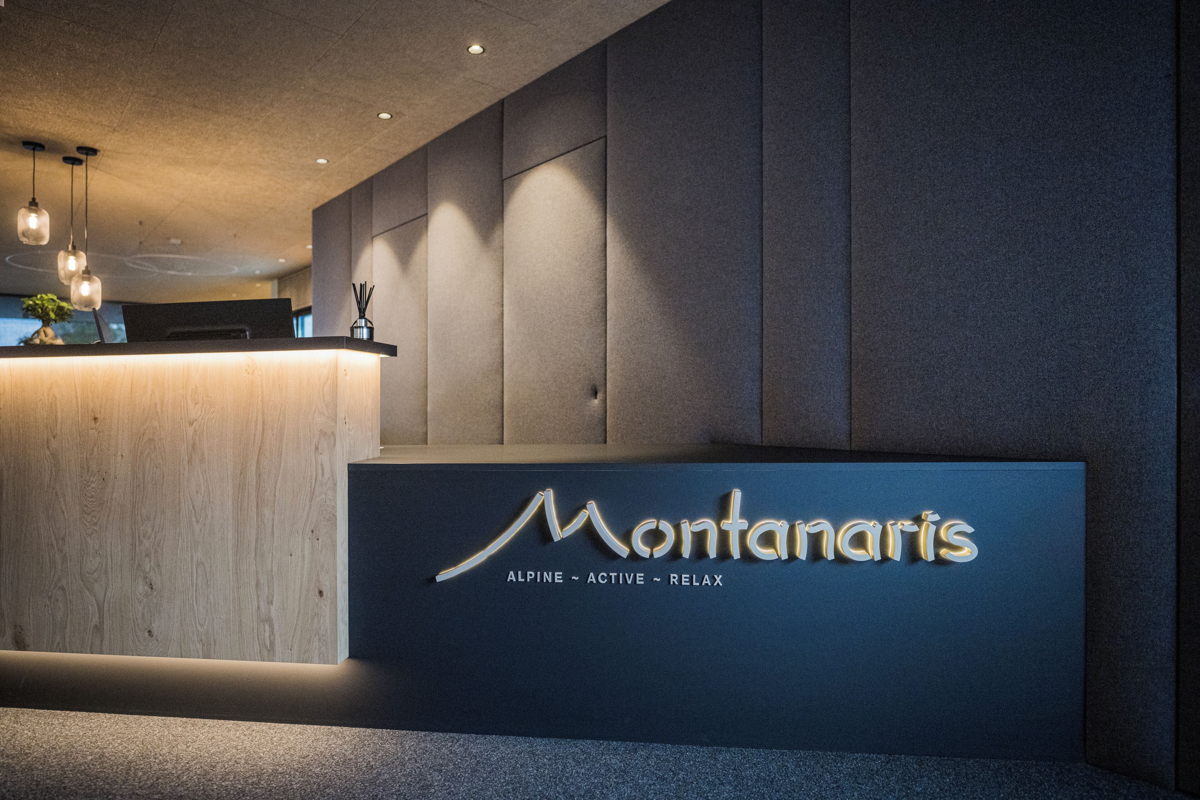 A reception desk with a sign reading "Montanaris" and the words "ALPINE - ACTIVE - RELAX" below it.