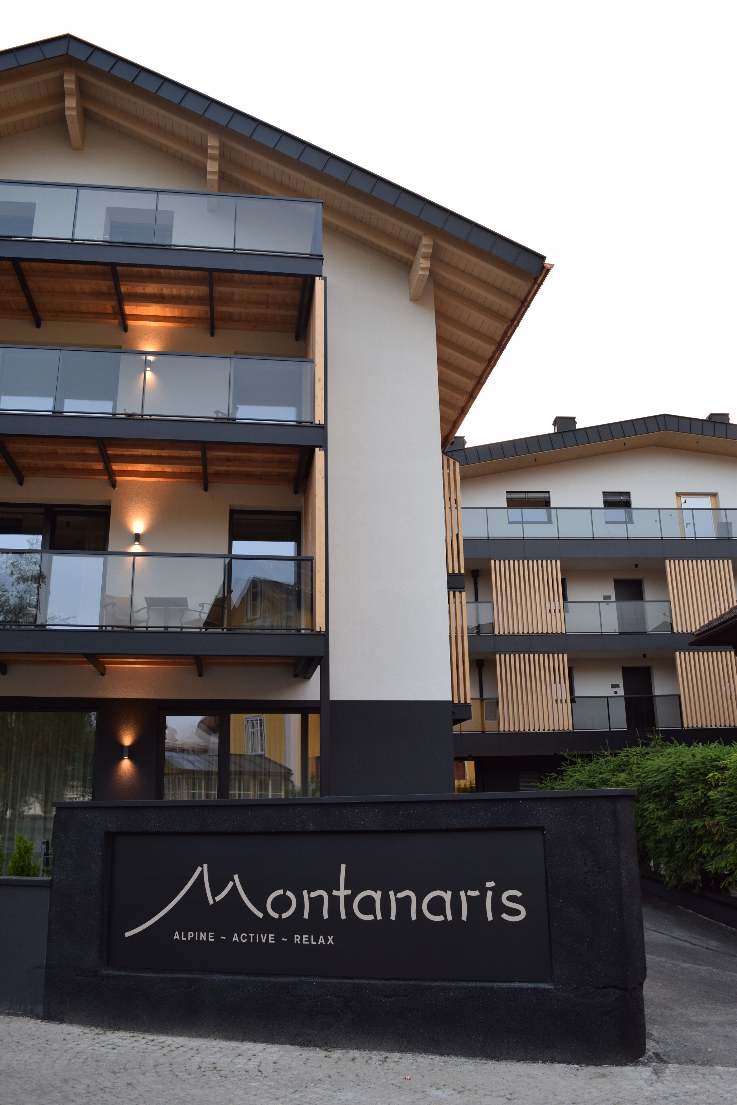 A modern multi-story building with balconies, a sign reading "Montanaris," and a clear sky.