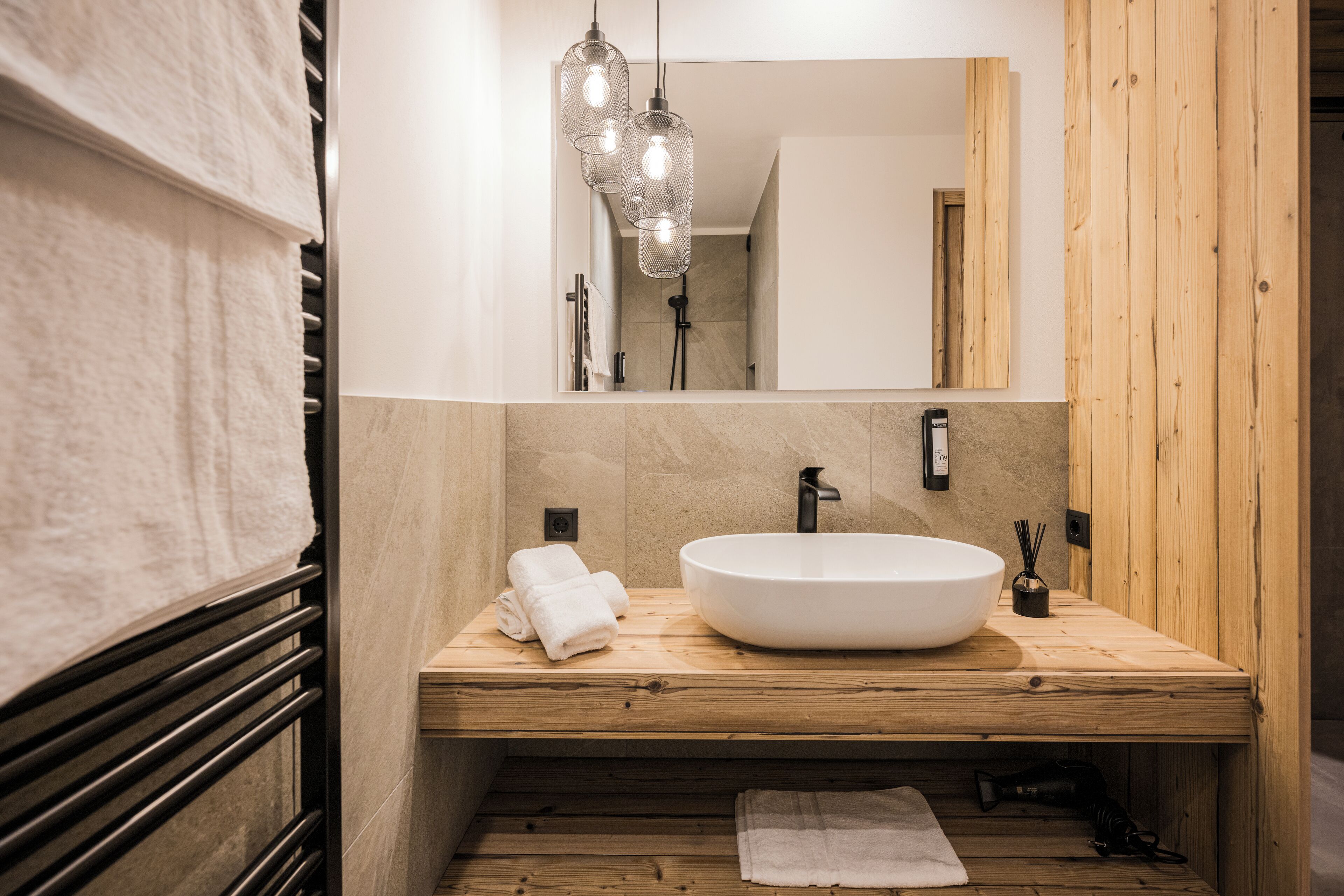 A modern bathroom with a wooden vanity, a large sink, and a mirror.