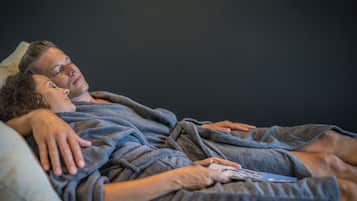 A couple lying in bed, covered with a blanket.
