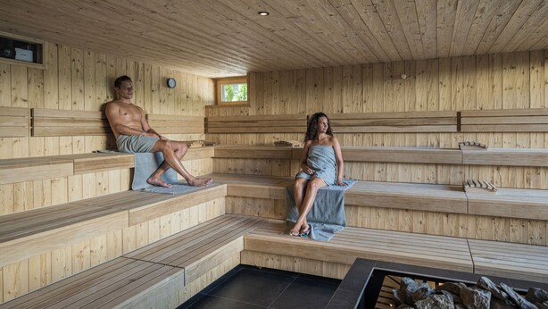 Uma sauna de madeira com bancos e piso de pedra.