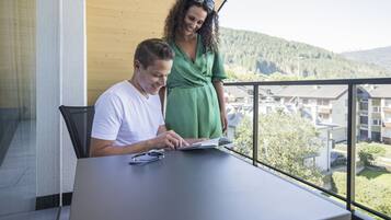 Ein Mann und eine Frau sitzen an einem Tisch mit Blick auf eine Wohngegend und Hügel im Hintergrund.