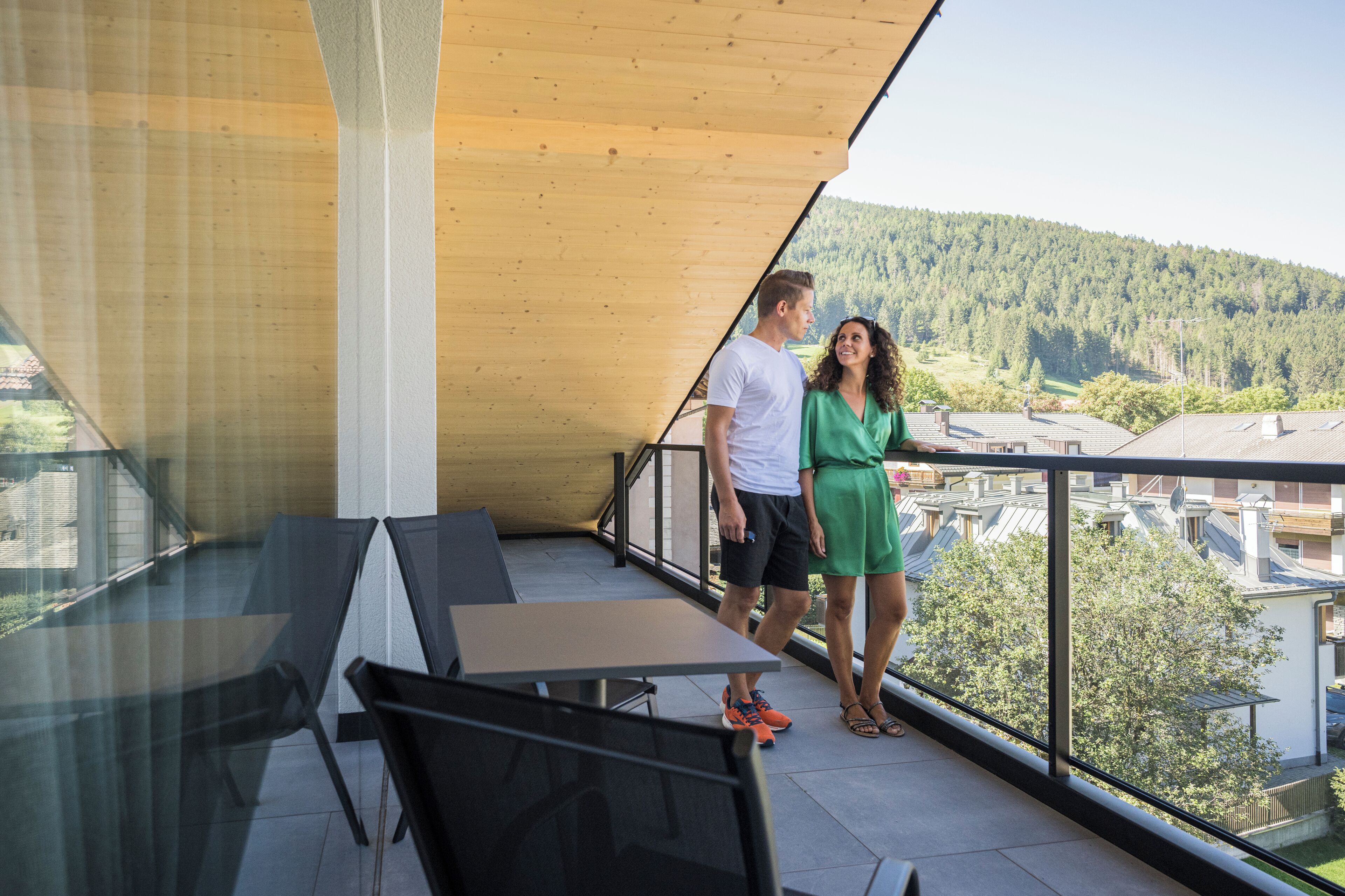 A balcony with a glass railing, a table, and chairs.