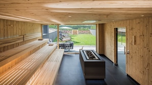 Uma área de spa moderna com paredes de madeira, piso aquecido e vista para um jardim.