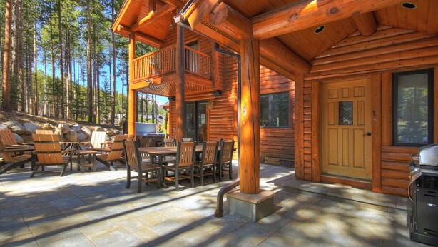 A log cabin with a deck, outdoor seating, and a stone patio. - Boulder Lodge At Peak 8 4 Bedroom Home by RedAwning (Breckenridge)