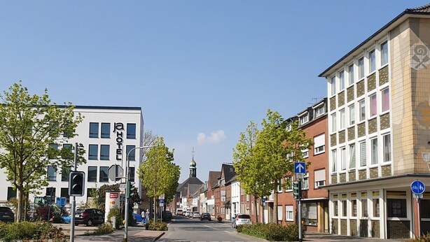 Vista de una calle con un hotel, una iglesia y edificios residenciales.
