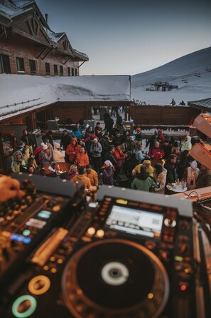 A group of people gathered around a fire pit in a snowy outdoor setting with a building in the background. - Magna Pivot Hotels - Boutique Class (Kayseri)