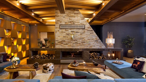 A modern living room with a stone fireplace, wooden ceiling beams, and a variety of seating options. - Magna Pivot Hotel - Boutique Class (Kayseri)