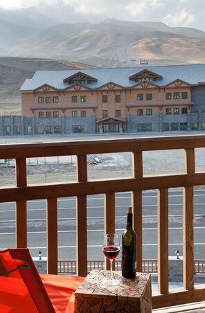 A table with a bottle of wine and a glass, overlooking a parking area and a building with a blue roof. - Magna Pivot Hotels - Boutique Class (Kayseri)