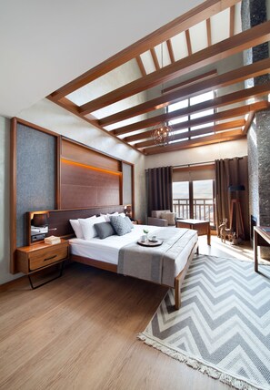 Une chambre moderne avec un plafond en bois, un grand lit, un bureau et une vue sur l’extérieur.