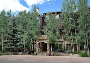 Aspenwood Lodge with a stone facade, multiple balconies, and a stone staircase leading to the entrance.