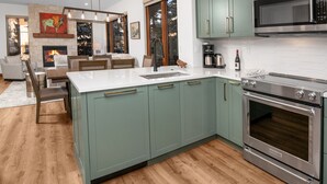 Une cuisine moderne avec des meubles de couleur verte, des appareils en acier inoxydable et un îlot central.
