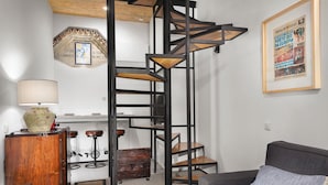 A modern living room with a spiral staircase, a vintage lamp, and a framed newspaper on the wall. - National Theater Houses 20 (Porto)