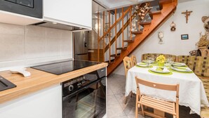 Eine moderne Küche mit einer Holztreppe, einem Essbereich mit gedecktem Tisch für zwei Personen und einer religiösen Statue an der Wand.