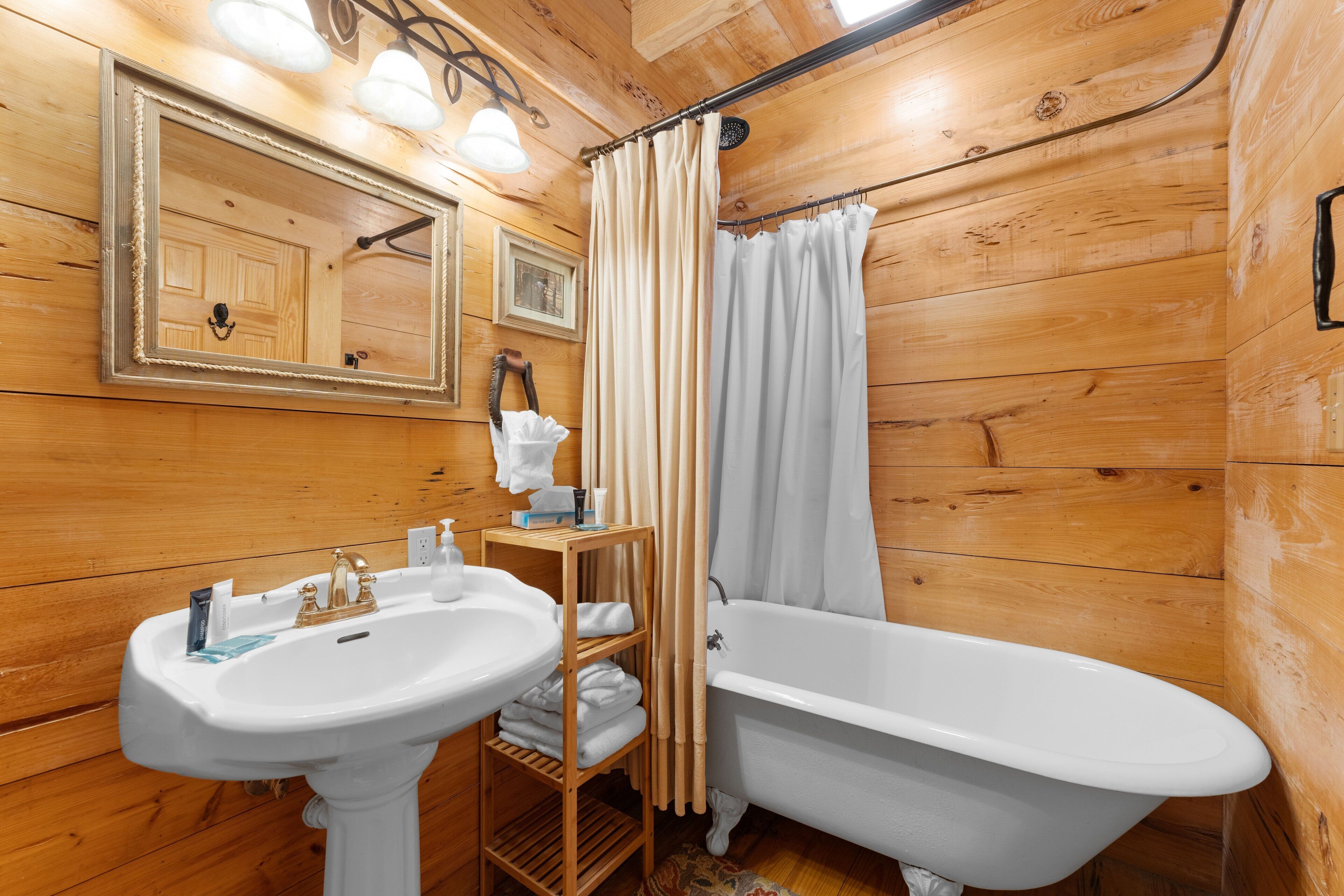Een badkamer met houten lambrisering, een witte wastafel, een bad en een spiegel boven de wastafel.