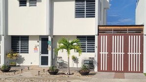 Ein modernes, zweistöckiges Gebäude mit flachem Dach, großen Fenstern und einer Garage mit schmiedeeisernem Tor.