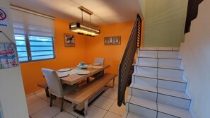 A dining area with a wooden table and benches, a staircase, and artwork on the walls.