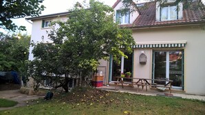 Un immeuble résidentiel doté d’un jardin, d’un banc en bois et d’une cage à oiseaux sur le balcon.