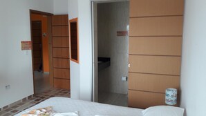 Une chambre d’hôtel comprenant un lit, une salle de bain avec des toilettes et un lavabo, et une armoire.