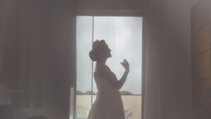 La silhouette d’une personne se tenant dans l’encadrement d’une porte, avec vue sur un balcon à l’extérieur.