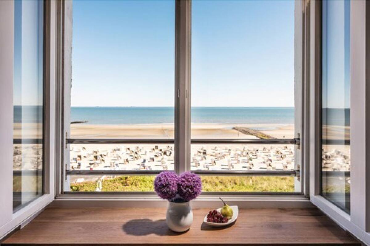 A room with a large window overlooking a beach.