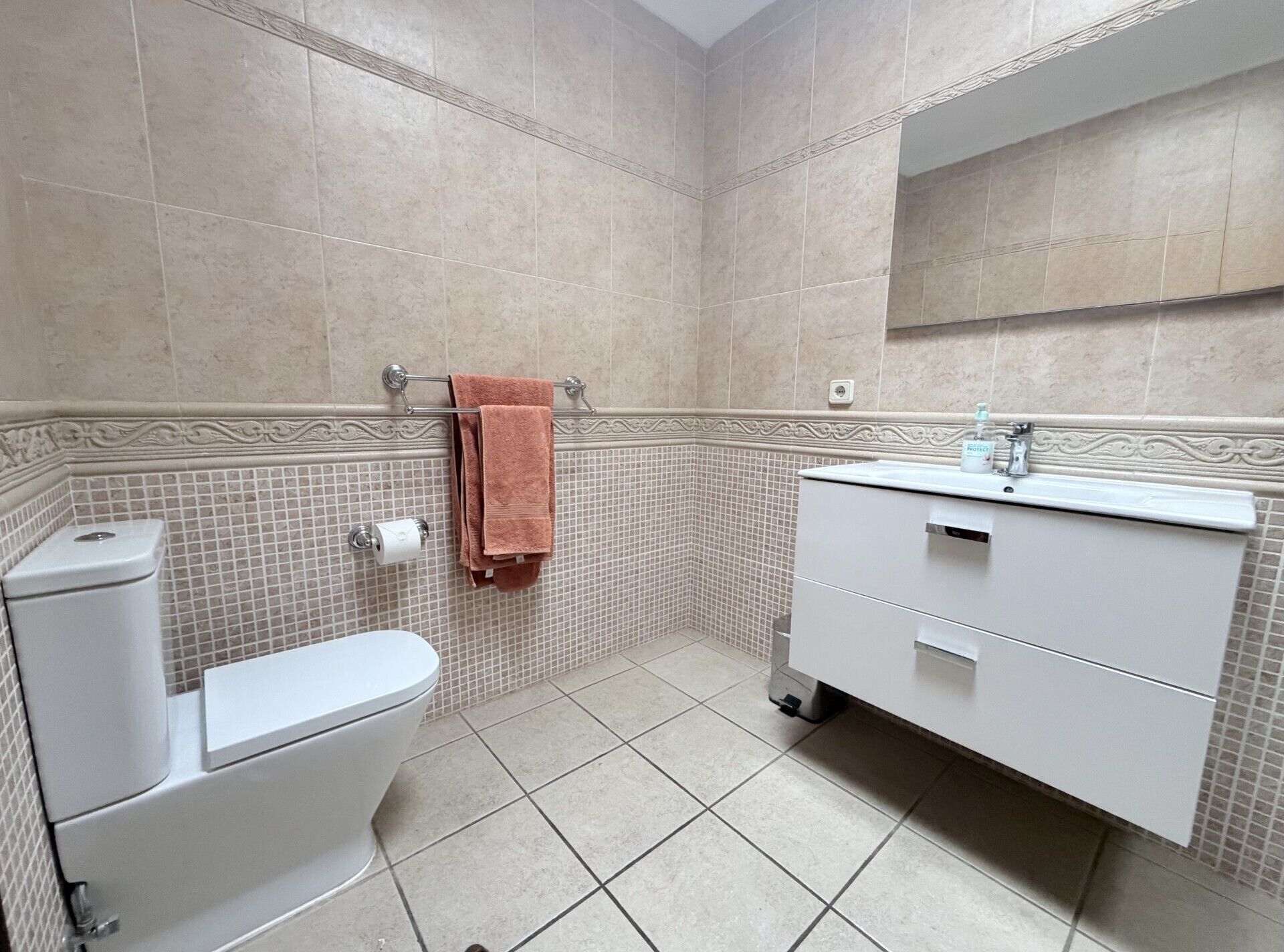 A bathroom with a toilet, sink, and mirror.