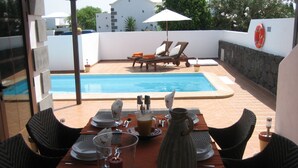 Un espace repas avec une piscine en arrière-plan.
