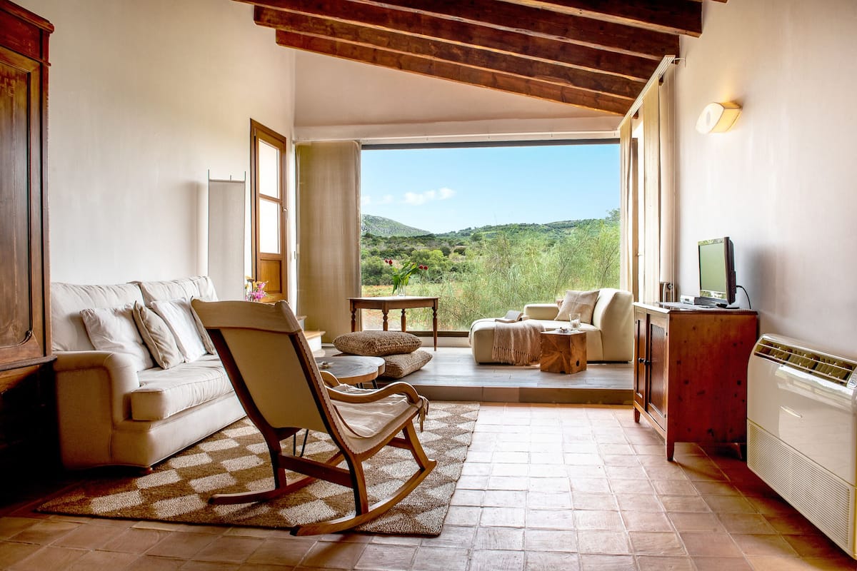 Una sala de estar acogedora con un sillón mecedora, un sofá y un mueble para televisión.