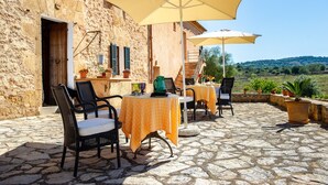An outdoor patio with stone flooring, tables with yellow tablecloths, and chairs. - Finca Sos Ferres D'en Morey (Manacor)